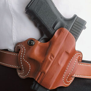 Black semi-automatic handgun secured in a brown leather holster on a belt against a white shirt background.